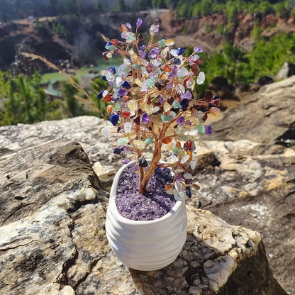 This is the right side of this multi-gemstone crystal  tree in white container sitting on a boulder