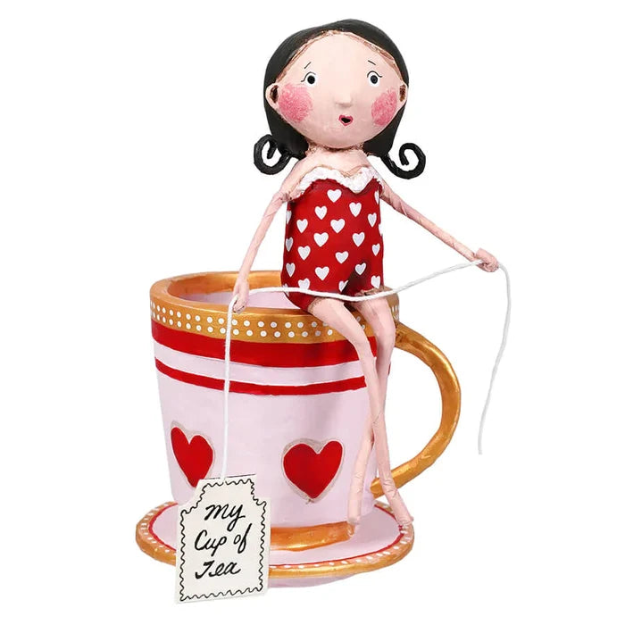 A resin figurine of a woman in a red swimsuit with white hearts, sitting on a large teacup with hearts, holding a cup with the text 'my cup of tea'.