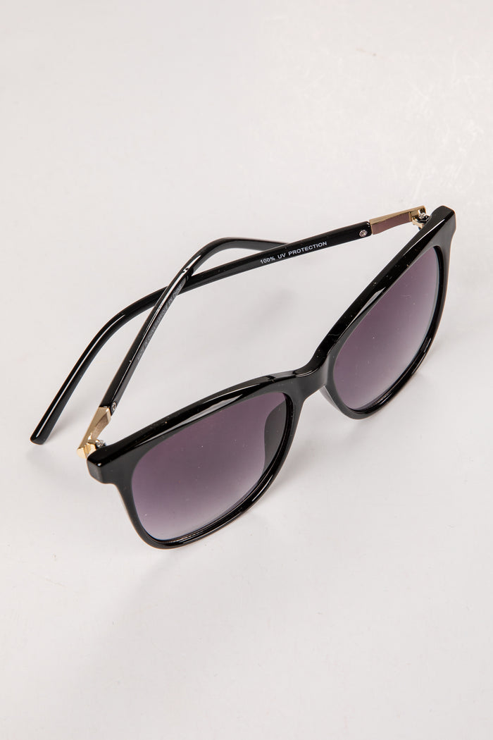 Black cat-eye sunglasses with gold accents on a white background