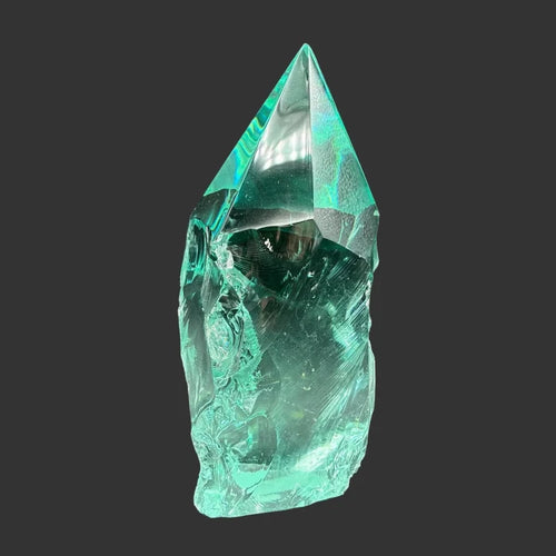 Front side of this blue green slag freeform, in front of a black background.