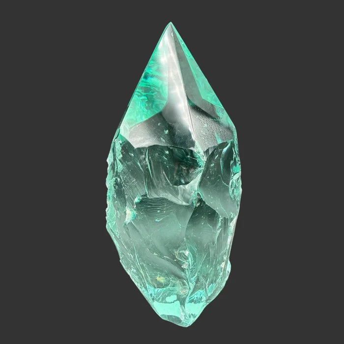 Back side of this blue green slag glass freeform, in front of a black background.